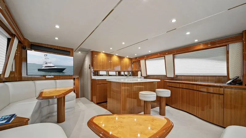 Slide: The Image of Elegant Salon with Dining Area The salon of the 2015 Viking 55 Convertible exudes luxury with its polished wood finishes and soft, neutral upholstery. Ample natural light floods through large windows, enhancing the spacious feel of the open-plan layout. The central dining area features - 7584864