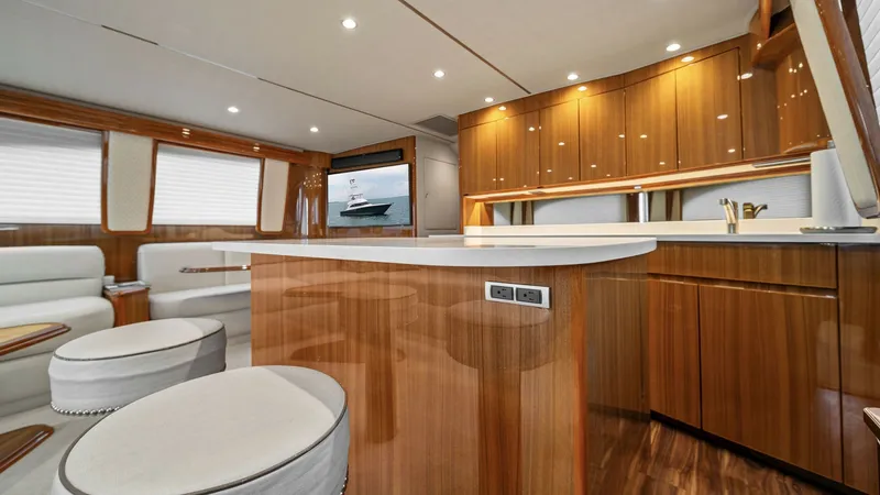 Slide: The Image of Spacious Salon and Galley Area This inviting salon and galley area on the 2015 Viking 55 Convertible 'Rosita' features elegant wood finishes and contemporary design. The open layout includes plush seating and a sleek entertainment system, providing a comfortable space for relaxation. T - 7584866