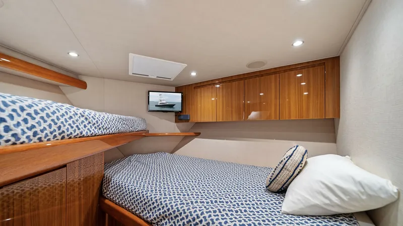 Slide: The Image of Guest Cabin with Bunk Beds This inviting guest cabin on the 2015 Viking 55 Convertible features cozy bunk beds with stylish, patterned bedding. The space is accented by polished wood cabinetry, offering ample storage and a touch of elegance. Recessed lighting and a wall-mounted tel - 7584887