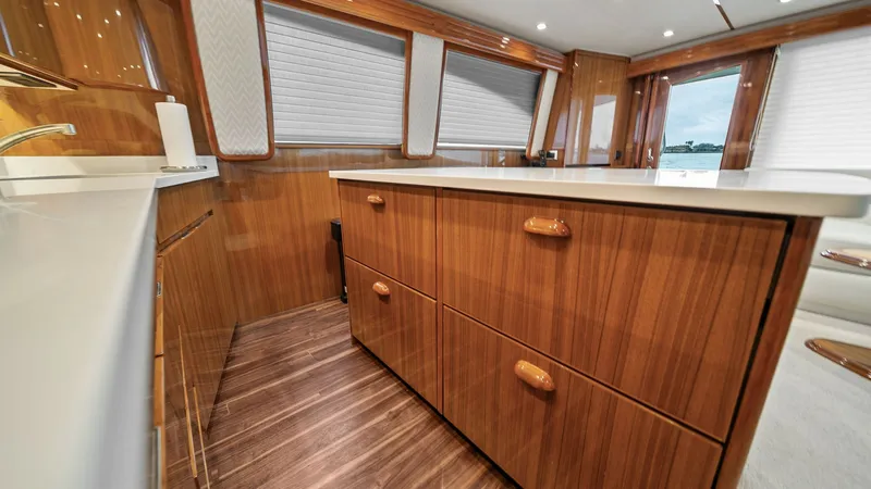 Slide: The Image of Galley with Elegant Wood Cabinetry The galley of the 2015 Viking 55 Convertible 'Rosita' features exquisite wood cabinetry and a sleek countertop, offering a perfect blend of functionality and style. The ample storage space is complemented by a modern, streamlined design, creating a welcom - 7584870