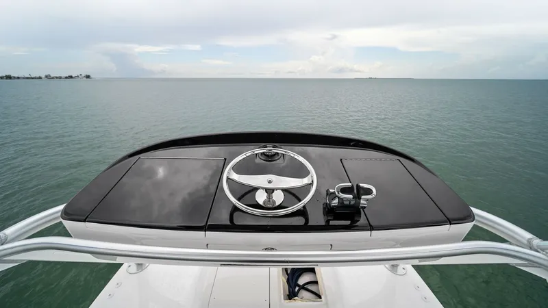 Slide: The Image of Flybridge Helm Station The flybridge helm station of the 2015 Viking 55 Convertible 'Rosita' offers a commanding view of the open sea. Featuring a sleek black console with a modern steering wheel and throttle controls, it ensures precise navigation. This elevated position provi - 7584911