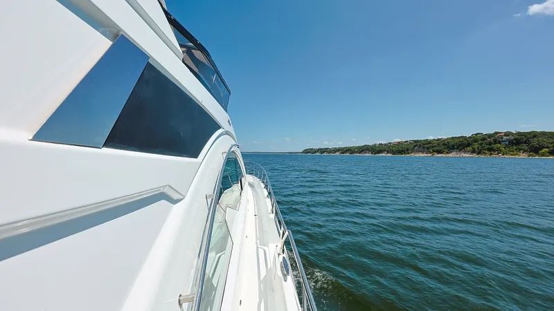 Slide: The Image of Starboard Side View with Ocean Horizon This image captures the sleek starboard side of the 2020 Cruisers 60 Cantius, showcasing its modern design and elegant lines. The expansive windows reflect the clear blue sky, allowing natural light to flood the interior while offering panoramic views. Th - 7661175