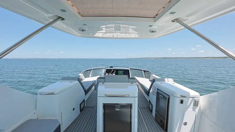 Slide: The Image of Spacious Cockpit with Ocean View The cockpit of the 2020 Cruisers 60 Cantius offers a luxurious open layout with ample seating and a commanding view of the sea. The sleek flooring and modern design provide both functionality and style, while the overhead canopy ensures comfort and shade. - 7661169