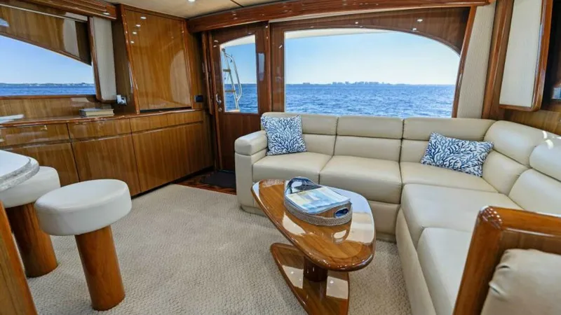 Slide: The Image of Luxurious Main Salon with Ocean View The main salon of the 2013 Viking 55 Convertible showcases a beautifully crafted interior with plush L-shaped seating and rich wood finishes. Large windows offer panoramic ocean views, enhancing the open and airy ambiance. The elegant coffee table and sop - 7594235