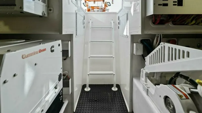Slide: The Image of Engine Room Access Ladder This image showcases the engine room access area of the 2013 Viking 55 Convertible. The space is equipped with robust machinery, including a Cummins Onan generator, ensuring reliable onboard power. The ladder provides easy access for maintenance, with a w - 7594299