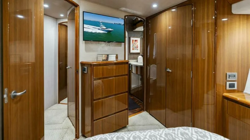Slide: The Image of Master Stateroom with Ensuite Access The master stateroom of the 2013 Viking 55 Convertible exudes luxury with its high-gloss wood finishes and elegant cabinetry. The room offers ample storage with built-in drawers and a spacious wardrobe. Soft ambient lighting and a flat-screen TV provide a - 7594248