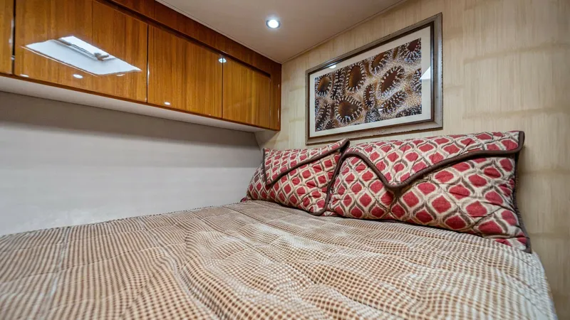 Slide: The Image of Cozy Guest Stateroom This inviting guest stateroom on the 2013 Viking 55 Convertible features a plush double berth with stylish patterned bedding. The warm wooden cabinetry provides ample storage, while recessed lighting and a decorative framed artwork enhance the room's ambi - 7962076