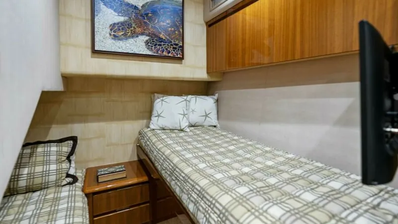 Slide: The Image of Guest Stateroom with Twin Beds The guest stateroom features comfortable twin beds with plaid bedding, providing a cozy retreat for guests. Warm wood cabinetry and paneling add a touch of elegance, while the wall-mounted artwork enhances the room's inviting atmosphere. A small bedside t - 7594245