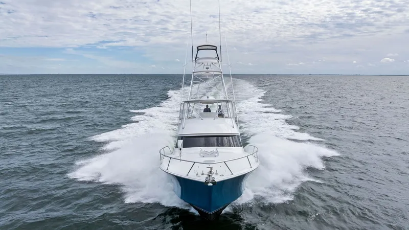 Slide: The Image of Bow View on Open Water This image captures the dynamic bow view of the 2013 Viking 55 Convertible, 'Hot Spot', as it cuts through open waters. The sleek hull design and powerful engines create an impressive wake, showcasing the vessel's performance capabilities. The flybridge i - 7962122