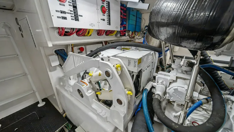 Slide: The Image of Engine Room with Control Panel This image showcases the engine room of the Viking 55 Convertible, featuring a neatly organized control panel with prominent red emergency stop buttons and labeled switches. The space is meticulously maintained, highlighting the vessel's commitment to per - 7962107