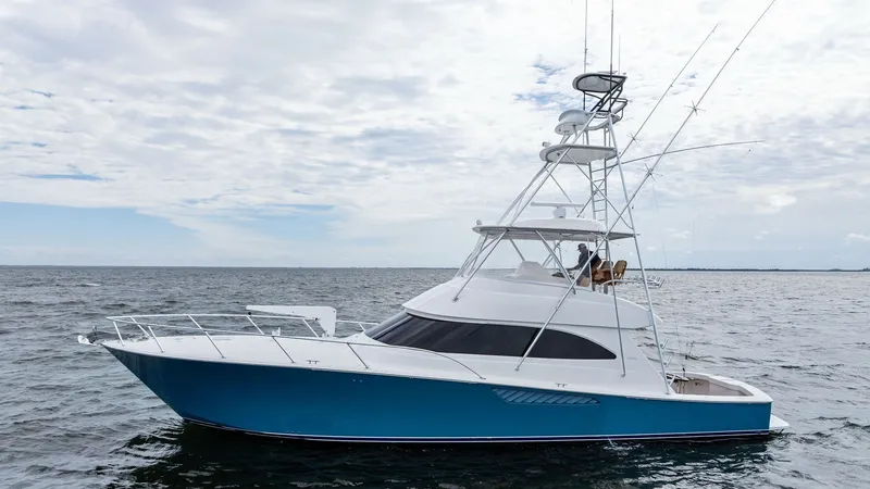Slide: The Image of Starboard Profile of Viking 55 Convertible This image showcases the sleek starboard profile of the 2013 Viking 55 Convertible, named 'Hot Spot'. The vessel's striking blue hull contrasts beautifully with its white superstructure, highlighting its elegant lines and robust build. The flybridge is eq - 7962114