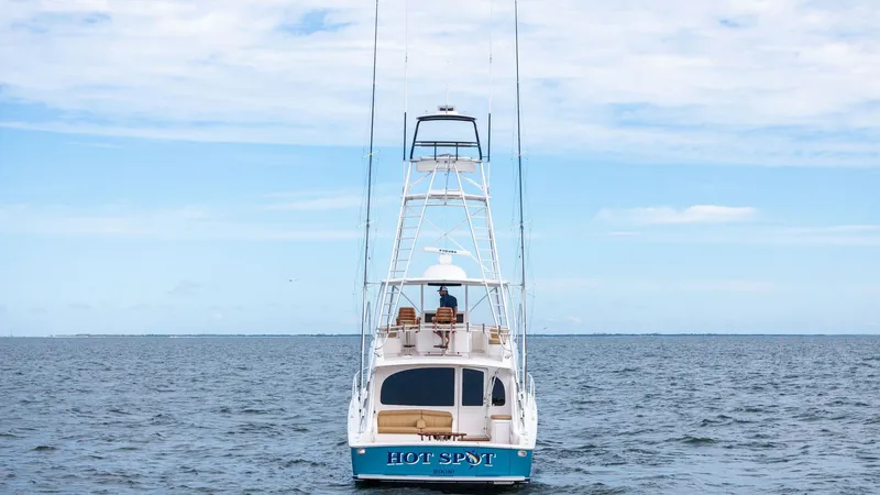 Slide: The Image of Aft View with Tower and Cockpit This image showcases the aft view of the 2013 Viking 55 Convertible, 'Hot Spot'. The vessel features a spacious cockpit, ideal for fishing or leisure, with an inviting seating area for relaxation. The prominent tuna tower enhances visibility and navigatio - 7962117