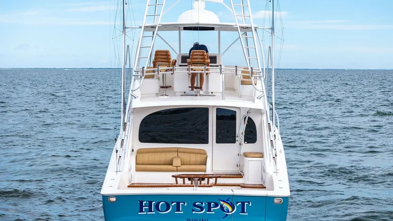 Slide: The Image of Aft View with Flybridge Seating This image showcases the inviting aft view of the 2013 Viking 55 Convertible, 'Hot Spot'. The spacious cockpit is complemented by a comfortable bench seat, ideal for relaxation or fishing activities. Above, the flybridge offers helm seating with panoramic - 7962116