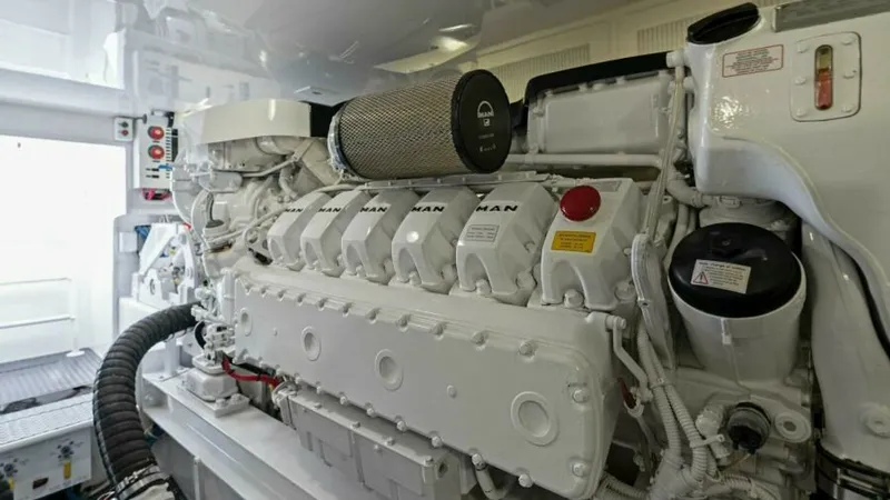 Slide: The Image of Engine Room with MAN Engines The engine room of the 2013 Viking 55 Convertible 'Hot Spot' showcases powerful MAN engines, meticulously maintained for optimal performance. The space is well-organized, with a clean, white finish that enhances visibility and accessibility. Modern engine - 7594296