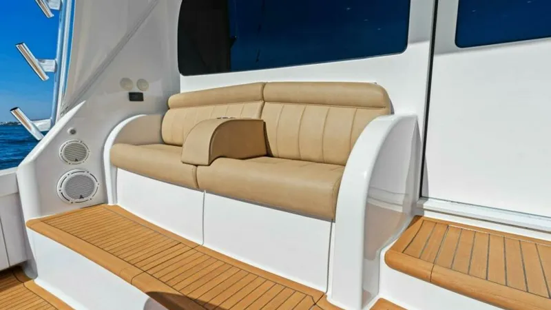 Slide: The Image of Cockpit Seating Area with Steps This image showcases the elegant cockpit seating area of the Viking 55 Convertible. The plush, tan upholstered bench offers comfortable seating, complemented by the beautifully finished teak decking. The curved steps and sleek design provide easy access t - 7594264
