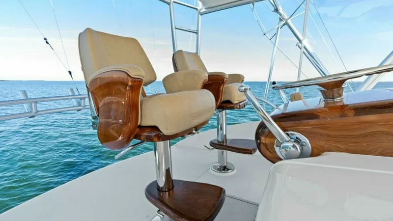 Slide: The Image of Flybridge Helm Seating and Controls This image showcases the elegant flybridge helm of the 2013 Viking 55 Convertible, featuring luxurious leather captain's chairs with polished wood accents. The helm is equipped with state-of-the-art controls, offering optimal comfort and functionality for - 7594280