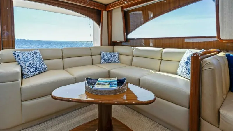 Slide: The Image of Luxurious Salon with Ocean View This elegant salon on the 2013 Viking 55 Convertible offers a plush L-shaped sofa complemented by tasteful decor. The expansive windows provide stunning ocean views, flooding the space with natural light. High-quality wood finishes and a sleek coffee tabl - 7594236