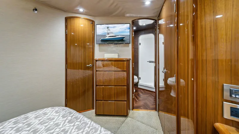 Slide: The Image of Guest Stateroom with Ensuite Access This inviting guest stateroom features warm wood finishes and elegant cabinetry, creating a cozy yet sophisticated atmosphere. The room is equipped with a plush bed and convenient access to an ensuite bathroom, ensuring privacy and comfort for guests. Rec - 7962070