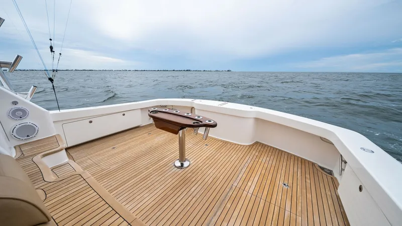 Slide: The Image of Spacious Teak Cockpit Deck View This image showcases the expansive teak cockpit deck of the 2013 Viking 55 Convertible, 'Hot Spot'. The space features a well-placed fighting chair, ideal for deep-sea fishing enthusiasts. The surrounding coaming bolsters and clean-lined gunnels enhance b - 7962086