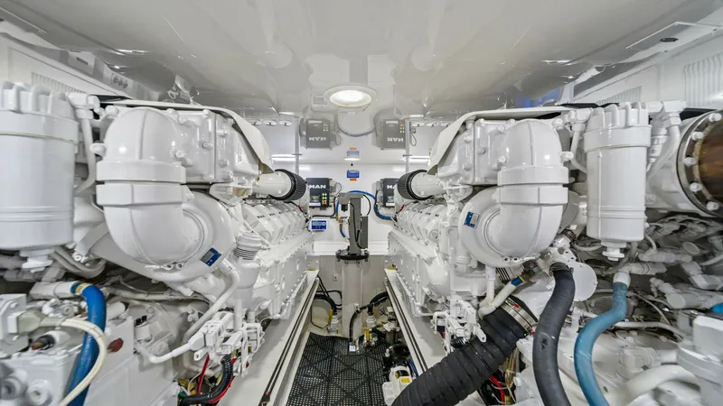 Slide: The Image of Engine Room with Twin Engines This image showcases the immaculate engine room of the Viking 55 Convertible, featuring twin powerful engines. The pristine white finish and organized layout enhance both functionality and accessibility for maintenance. Overhead lighting ensures the space - 7962108