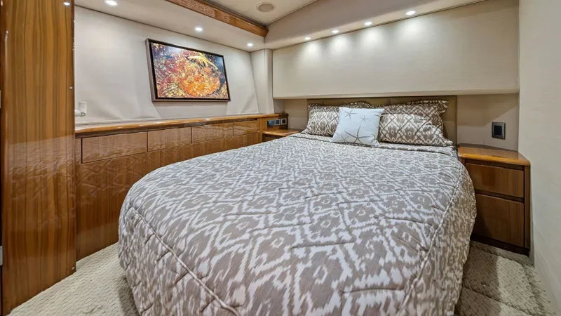Slide: The Image of Luxurious Master Stateroom This spacious master stateroom on the Viking 55 Convertible offers a serene retreat with its plush bedding and elegant wood finishes. Soft, ambient lighting enhances the cozy atmosphere, while ample storage is seamlessly integrated. A striking piece of ar - 7962069