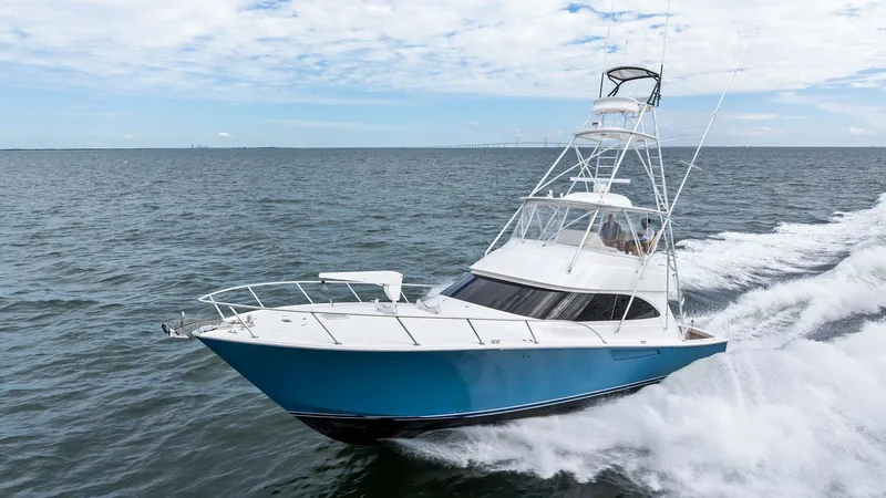 Slide: The Image of Dynamic Bow View Underway The 2013 Viking 55 Convertible 'Hot Spot' is captured slicing through the waves, showcasing its sleek and powerful design. The vibrant blue hull stands out against the ocean, while the flybridge with its commanding tower offers an excellent vantage point. - 7962123