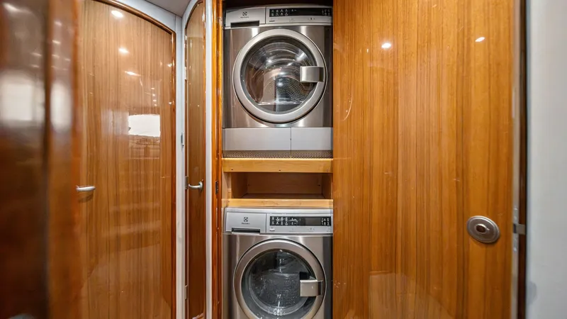 Slide: The Image of Laundry Area with Washer and Dryer This image showcases the efficient laundry area aboard the 2013 Viking 55 Convertible, 'Hot Spot'. It features a stacked washer and dryer set, elegantly integrated into a sleek wooden enclosure that complements the yacht's sophisticated interior. This pra - 7962074