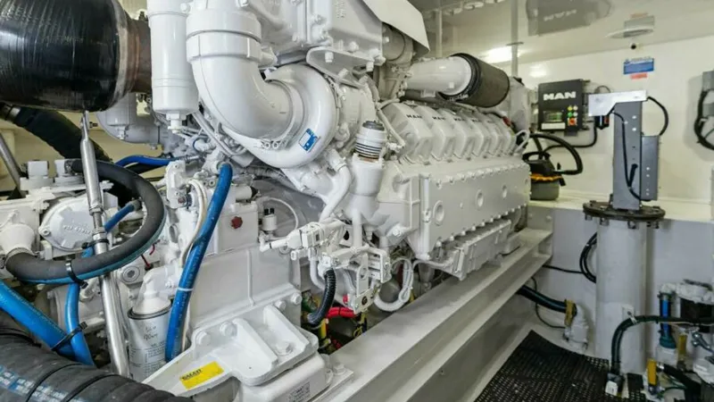 Slide: The Image of Engine Room with MAN V12 Engine The engine room of the 2013 Viking 55 Convertible features a powerful MAN V12 engine, showcasing the vessel's robust engineering. The space is meticulously organized, with clearly labeled components and efficient use of space, ensuring easy access for mai - 7594293