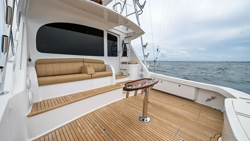 Slide: The Image of Spacious Teak Cockpit with Seating The cockpit of the 2013 Viking 55 Convertible 'Hot Spot' features elegant teak decking and a built-in cushioned bench, ideal for relaxation and socializing. This area is equipped with a sturdy fighting chair, perfect for sportfishing enthusiasts. The open - 7962085