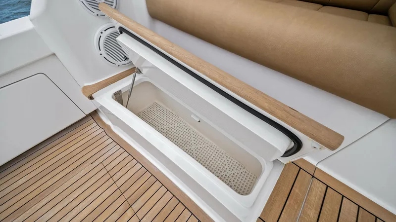 Slide: The Image of Cockpit Seating with Storage Compartment This image showcases the cockpit seating area of the 2013 Viking 55 Convertible, featuring a sleek integrated storage compartment. The seating is upholstered in a luxurious tan material, providing both comfort and style. The teak decking adds an elegant t - 7962092