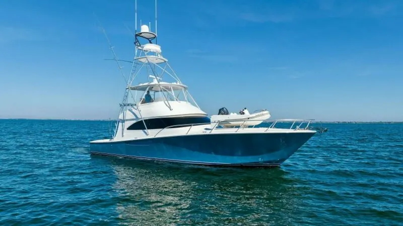 Slide: The Image of Viking 55 Convertible Exterior Profile The stunning exterior of the 2013 Viking 55 Convertible, 'Hot Spot,' is showcased in this image, highlighting its sleek hull design and commanding presence on the water. With a striking blue finish and a robust tower, this vessel is built for both luxury - 7594302