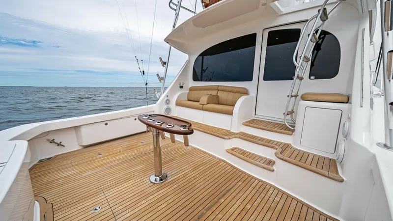 Slide: The Image of Spacious Teak Cockpit with Seating The 2013 Viking 55 Convertible features an expansive teak cockpit designed for both relaxation and sportfishing. The area is equipped with a comfortable cushioned bench seat and a versatile center table, ideal for gatherings or preparing gear. The well-cr - 7962084