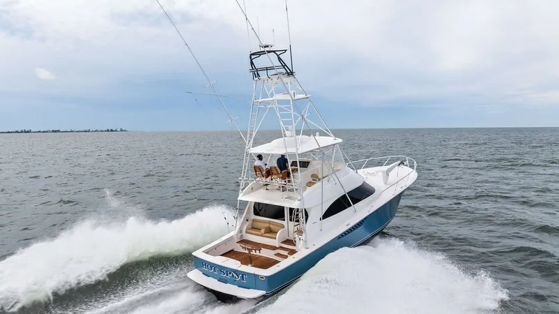 Slide: The Image of Aerial View of Aft Deck in Motion This image showcases the Viking 55 Convertible 'Hot Spot' from 2013, gliding through the water with impressive speed. The aft deck is visible, featuring a spacious layout with ample seating and rod holders, ideal for fishing enthusiasts. The sleek, blue h - 7962124