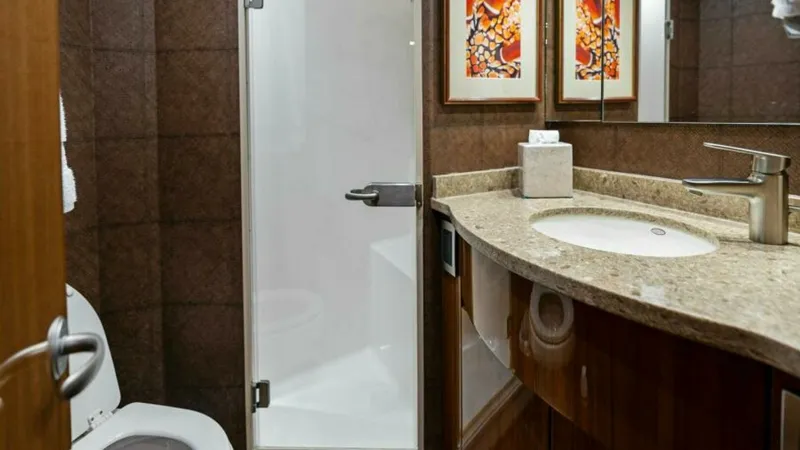 Slide: The Image of Luxurious Ensuite Bathroom This elegant ensuite bathroom aboard the 2013 Viking 55 Convertible 'Hot Spot' features a sleek, glass-enclosed shower complemented by modern fixtures. The curved vanity is topped with a polished stone surface, offering both style and functionality. Rich - 7594249