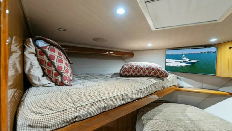 Slide: The Image of Cozy Twin Cabin with Ocean View This inviting twin cabin on the 2013 Viking 55 Convertible features plush bedding and stylish patterned pillows for ultimate comfort. The space is enhanced by warm wooden accents and ample natural light streaming through the side window, offering a pictur - 7594252