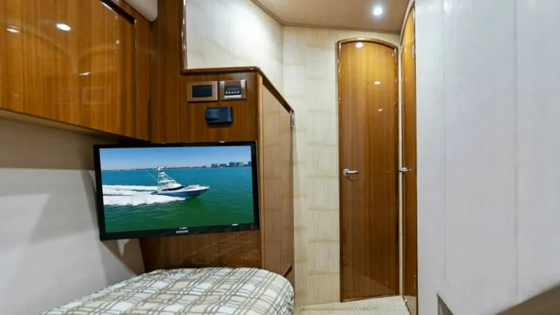 Slide: The Image of Guest Cabin with TV and Storage This inviting guest cabin on the 2013 Viking 55 Convertible 'Hot Spot' offers a cozy berth with contemporary plaid bedding. The space is enhanced by a mounted flat-screen TV, providing entertainment and relaxation for guests. Rich wood finishes and ambien - 7594246
