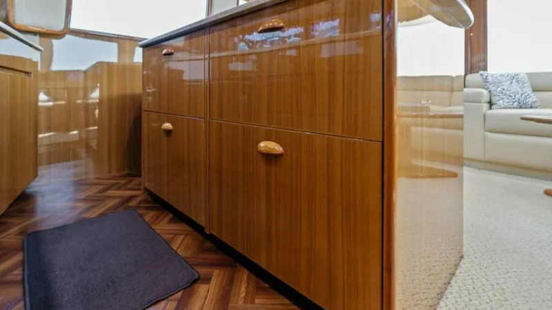 Slide: The Image of Galley with High-Gloss Cabinetry This image showcases the galley of the 2013 Viking 55 Convertible, featuring elegant high-gloss wooden cabinetry. The space is complemented by a sleek countertop, offering ample storage and functionality. The warm tones and polished finishes create an inv - 7594241
