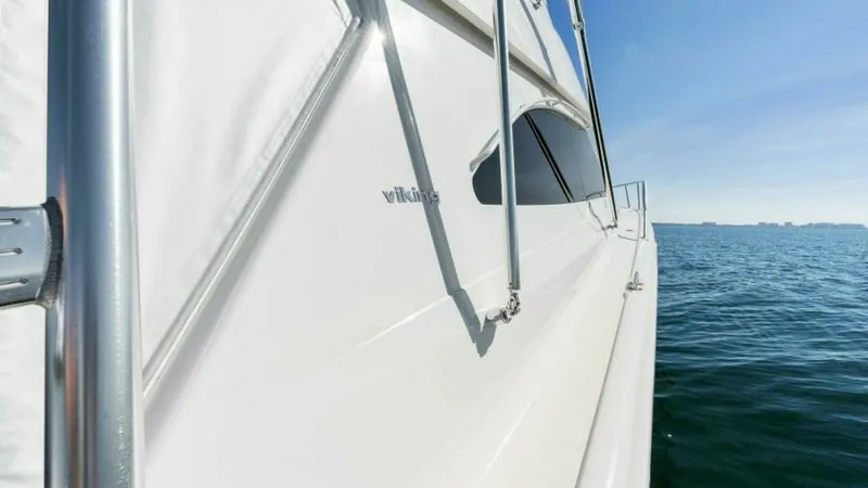 Slide: The Image of Starboard Side Deck View This image captures the sleek design of the starboard side deck of the 2013 Viking 55 Convertible. The polished stainless steel handrails and clean lines of the white hull emphasize the vessel's robust construction and elegant aesthetics. The expansive oc - 7594282