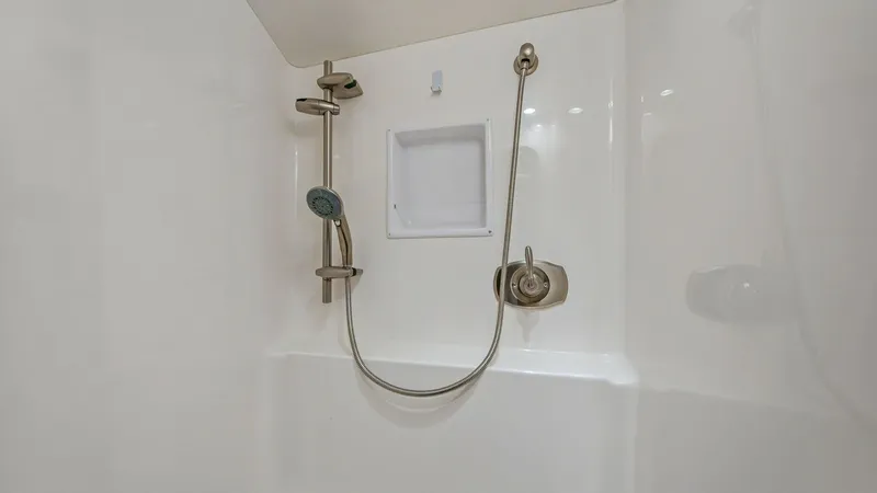 Slide: The Image of Enclosed Shower with Adjustable Head This image showcases the enclosed shower area of the 2013 Viking 55 Convertible. Featuring a sleek, built-in adjustable shower head and convenient shelving, this space is designed for both functionality and comfort. The clean, white finish adds a touch of - 7962081