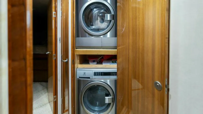 Slide: The Image of Laundry Area with Washer/Dryer This image showcases the well-appointed laundry area on the Viking 55 Convertible 'Hot Spot'. Featuring a stacked washer and dryer, this space is designed for convenience and efficiency. The elegant wood cabinetry adds a touch of luxury, seamlessly blendi - 7594255