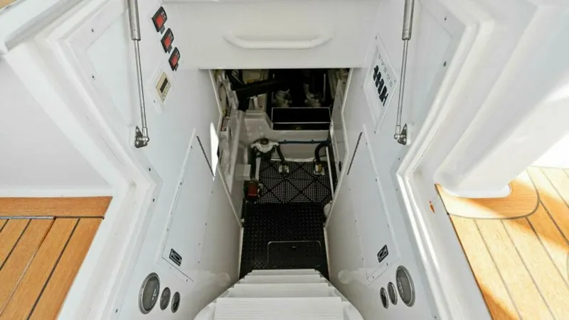 Slide: The Image of Engine Room Access Hatch This image showcases the engine room access hatch of the 2013 Viking 55 Convertible, 'Hot Spot.' The entrance is neatly integrated into the vessel's design, with sturdy steps and a clean, well-organized panel layout. The teak decking surrounding the hatch - 7594281