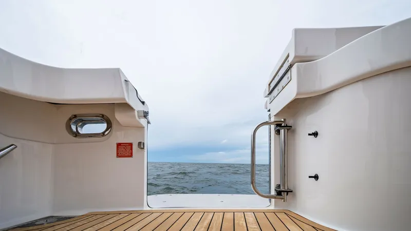 Slide: The Image of Stern View with Teak Decking This image captures the sleek design of the Viking 55 Convertible's stern, showcasing its elegant teak decking. The open transom provides a seamless flow to the ocean, perfect for fishing or enjoying the view. The polished stainless steel features and rou - 7962087