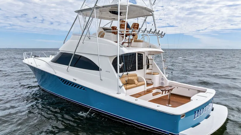 Slide: The Image of Aft Deck and Flybridge View This image showcases the aft deck and flybridge of the 2013 Viking 55 Convertible, 'Hot Spot'. The aft deck features a spacious seating area with plush cushions and a well-equipped fishing station, ideal for leisurely cruising or sportfishing. Above, the - 7962115