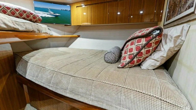 Slide: The Image of Cozy Guest Stateroom This inviting guest stateroom on the 2013 Viking 55 Convertible features a comfortable twin berth with elegant bedding and accent pillows. The polished wood cabinetry offers ample storage, complemented by soft ambient lighting for a warm and relaxing atmo - 7594253