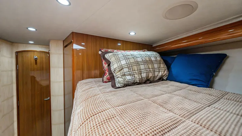 Slide: The Image of Cozy Guest Cabin with Bunk This inviting guest cabin features a comfortable bunk bed adorned with plaid and solid-colored pillows, creating a cozy retreat. The warm wood finishes on the cabinetry add a touch of elegance, complemented by soft recessed lighting. A neatly designed lay - 7962077