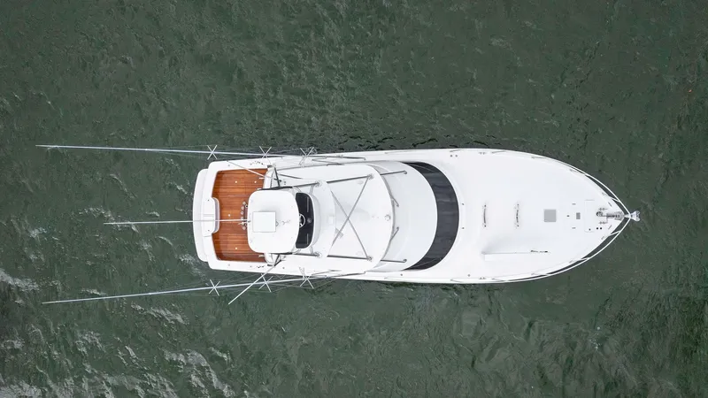 Slide: The Image of Aerial View of Flybridge and Deck This aerial shot of the 2013 Viking 55 Convertible 'Hot Spot' highlights its sleek lines and spacious flybridge. The deck features fine teak wood flooring, accentuating the yacht's luxurious appeal. The flybridge offers ample seating and a commanding view - 7962119