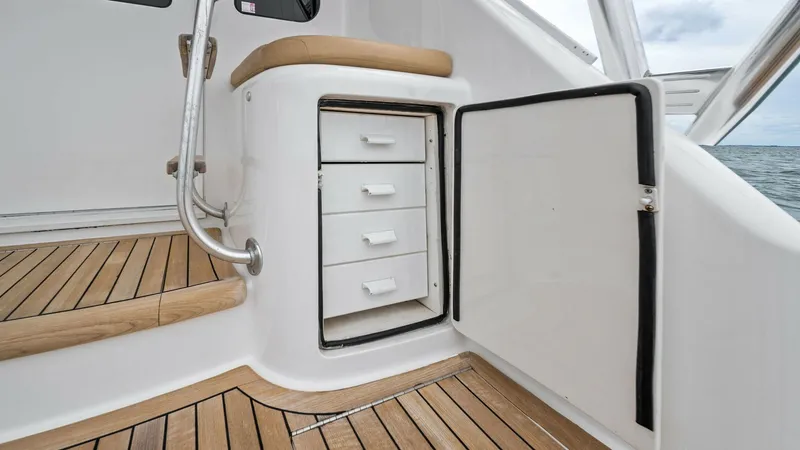 Slide: The Image of Cockpit Storage Area with Seating This image showcases the functional cockpit storage area of the 2013 Viking 55 Convertible. The compartment features multiple drawers for organized storage, seamlessly integrated into the sleek design. The adjacent cushioned seat provides comfort, while t - 7962093
