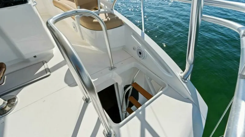 Slide: The Image of Flybridge Access Hatch and Seating Area This image showcases the flybridge access hatch on the Viking 55 Convertible. The sturdy stainless steel railings provide safety and support, while the nearby cushioned seating area offers comfort and relaxation. The clean, white deck contrasts beautifull - 7594262