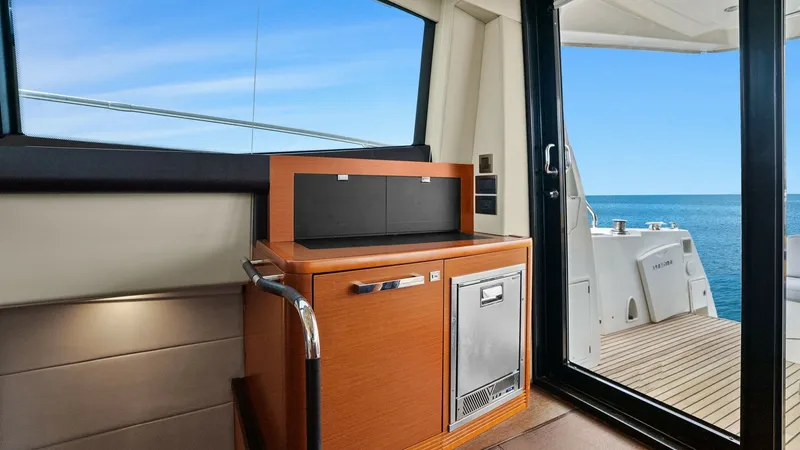 Slide: The Image of Galley and Aft Deck Access This image showcases the compact and efficient galley area adjacent to the aft deck of the Prestige 500 Fly. Featuring modern cabinetry and stainless-steel appliances, the space is designed for convenience and style. The large sliding glass door offers se - 7603787