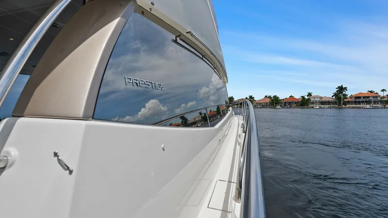 Slide: The Image of Starboard Side View with Reflections This image captures the sleek starboard side of the 2015 Prestige 500 Fly, showcasing its reflective windows and smooth exterior lines. The high-gloss finish mirrors the surrounding water and sky, emphasizing the yacht's elegant design. Stainless steel ra - 7603771